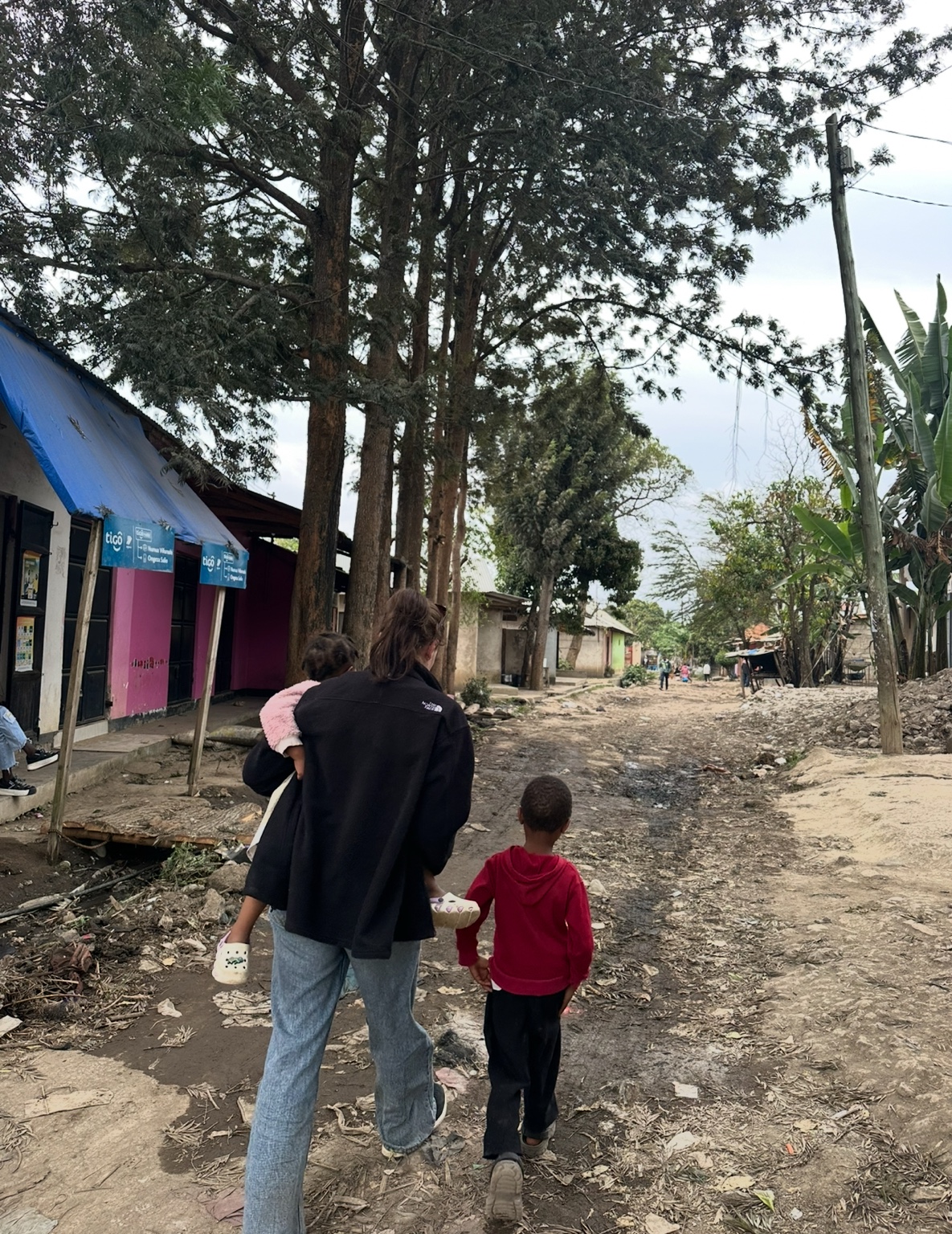 People walking together along a path through a neighbourhood in Arusha.